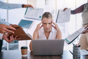 mujer con síntomas de estrés causado por el trabajo compañeros acosan con más tareas por realizar